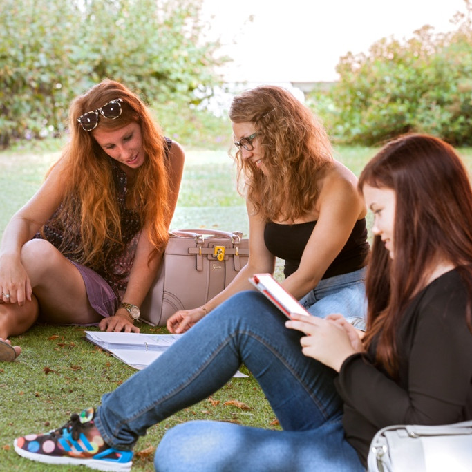 Studentinnen sitzend auf Wiese 