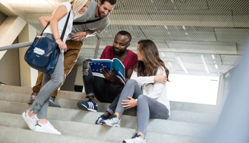 Studierende sitzen auf der Treppe