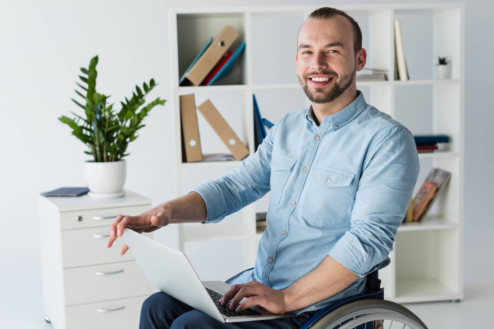 Junger Mann im Rollstuhl mit Laptop