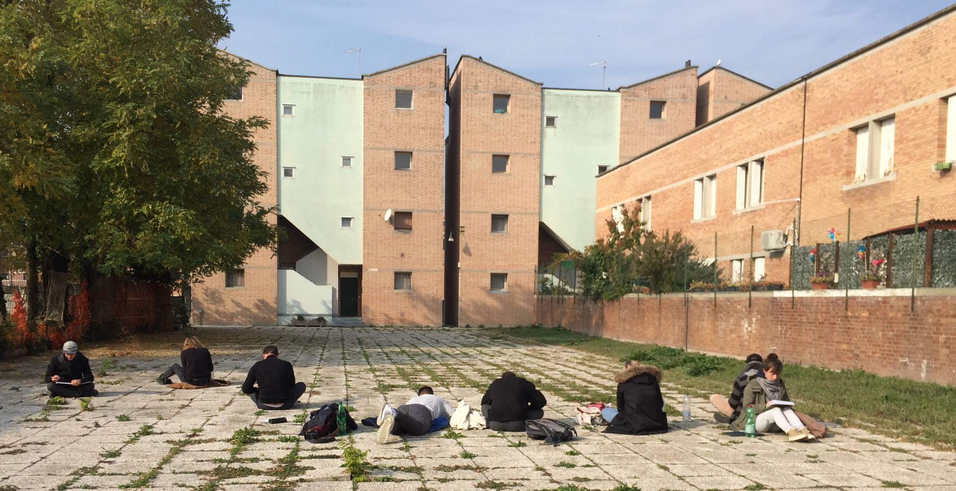 Studierende sitzen vor Gebäude und zeichnen dieses