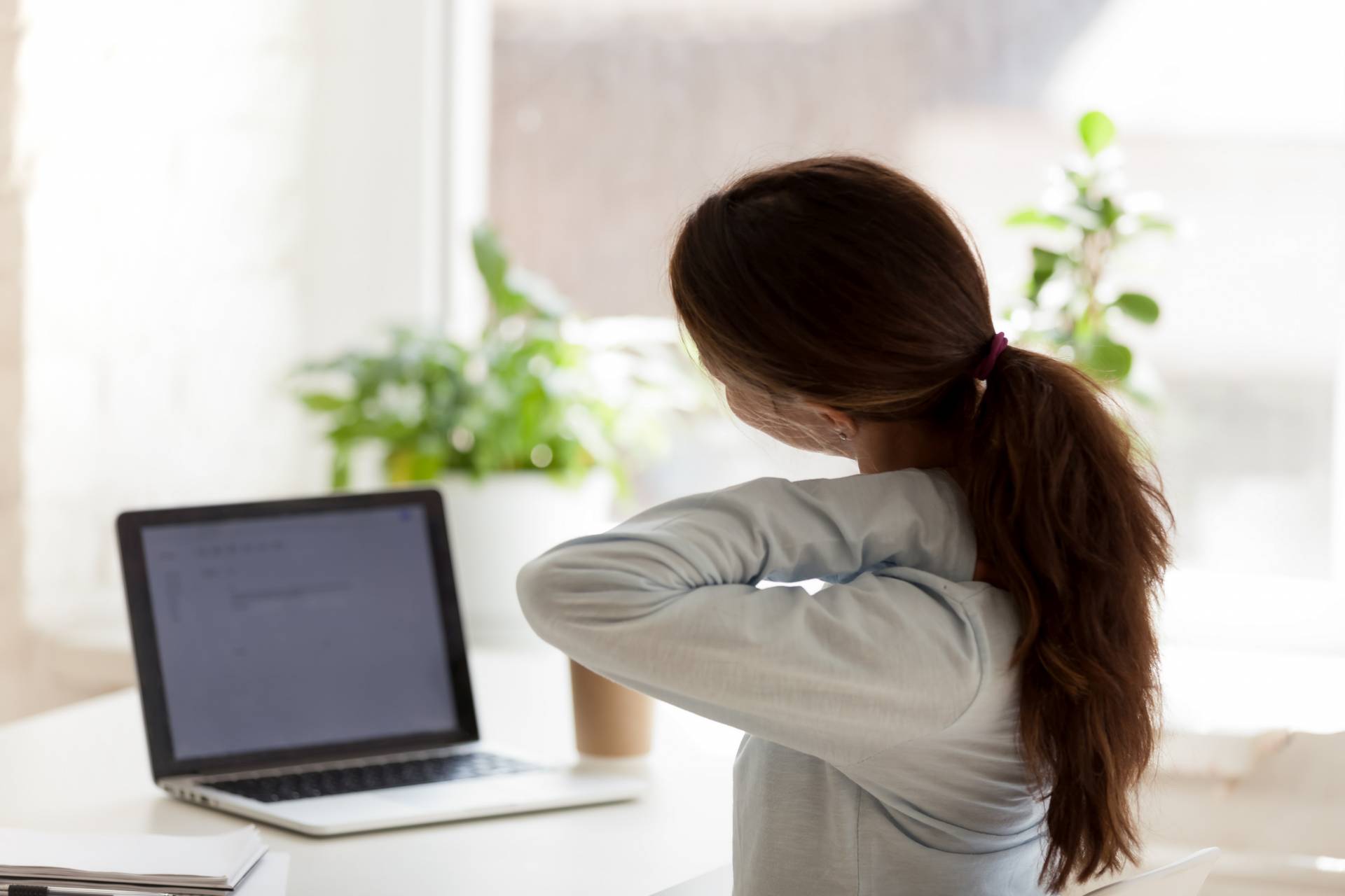 Frau vor dem Laptop mit Rückenschmerzen