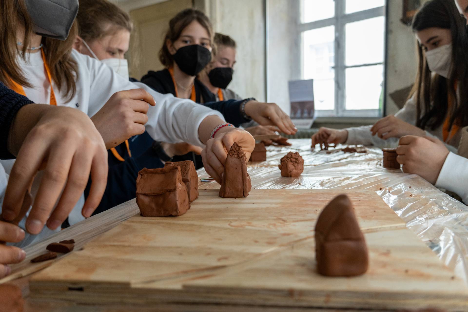 Schülerinnen bauen Skulpturen und Gebäude aus Lehm