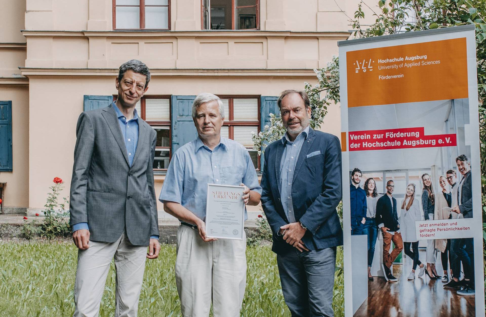 Prof. Dr. Wolfang Rommel (Mitte) bekommt von Ulrich Zuth (rechts), Vorstand des Vereins zur Förderung der Hochschule Augsburg e.V., und Vizepräsident László Kovács seine Stifterurkunde überreicht.