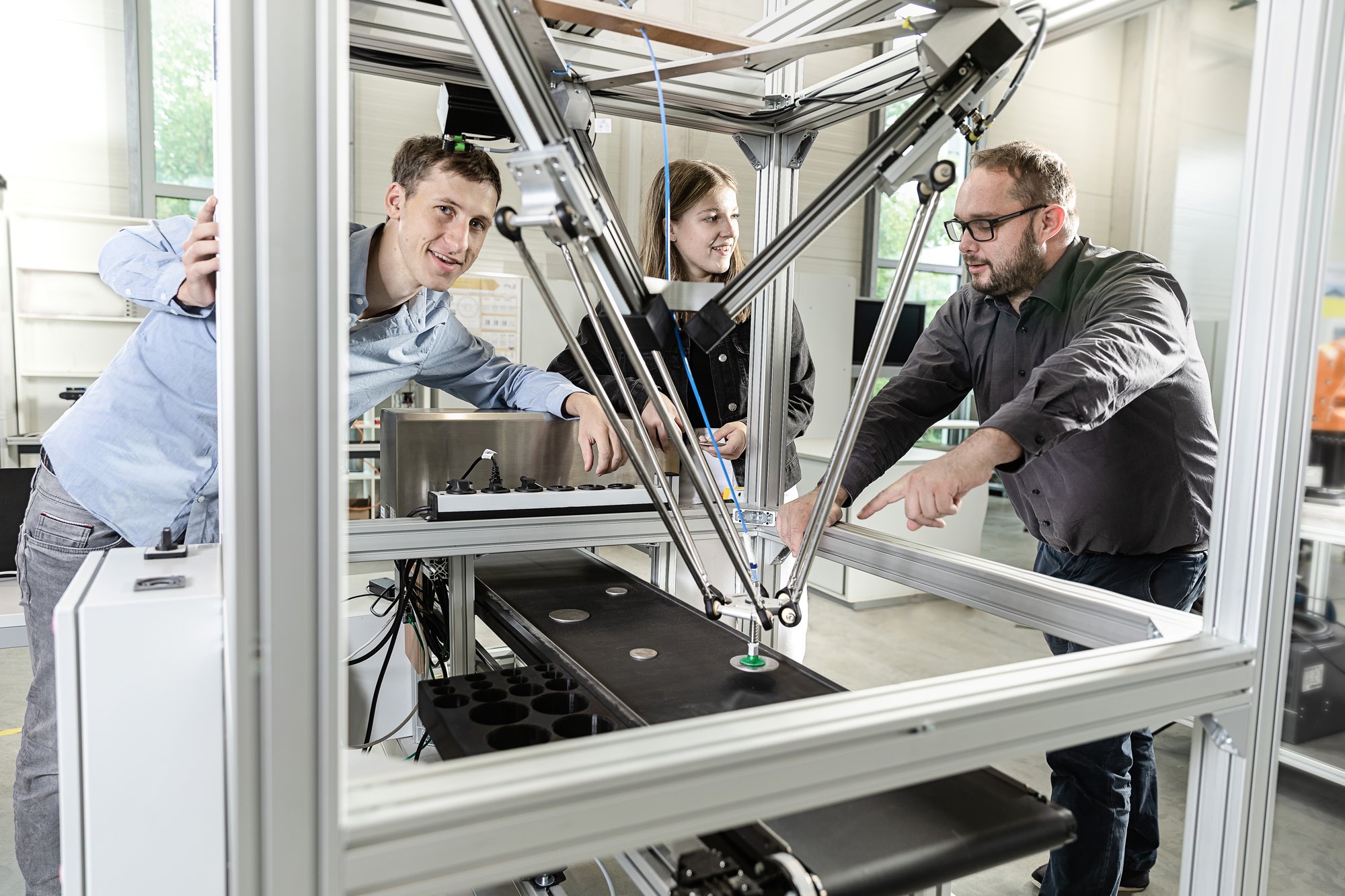 Mitarbeiter:innen und Studierende an einem automatischen Greifersystem