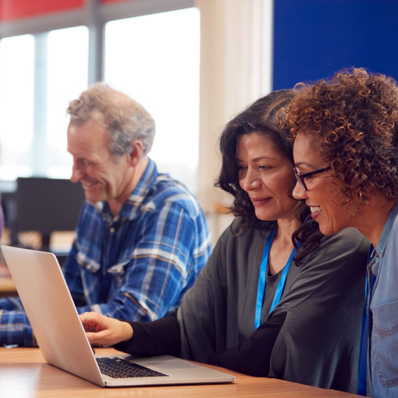 3 Personen sitzen vor einem Laptop