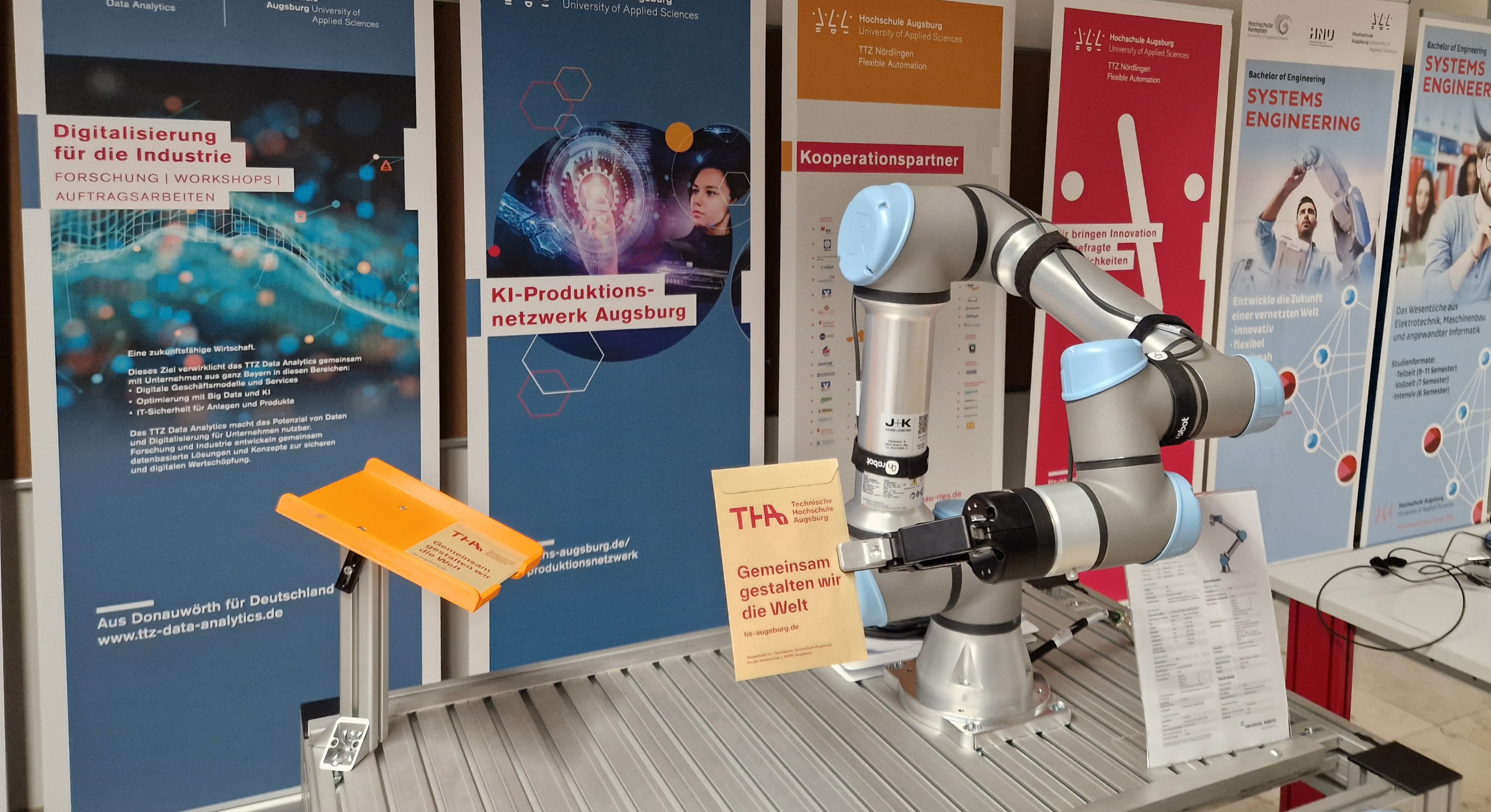 Stand mit Roboterarm, Roll-Ups im Hintergrund