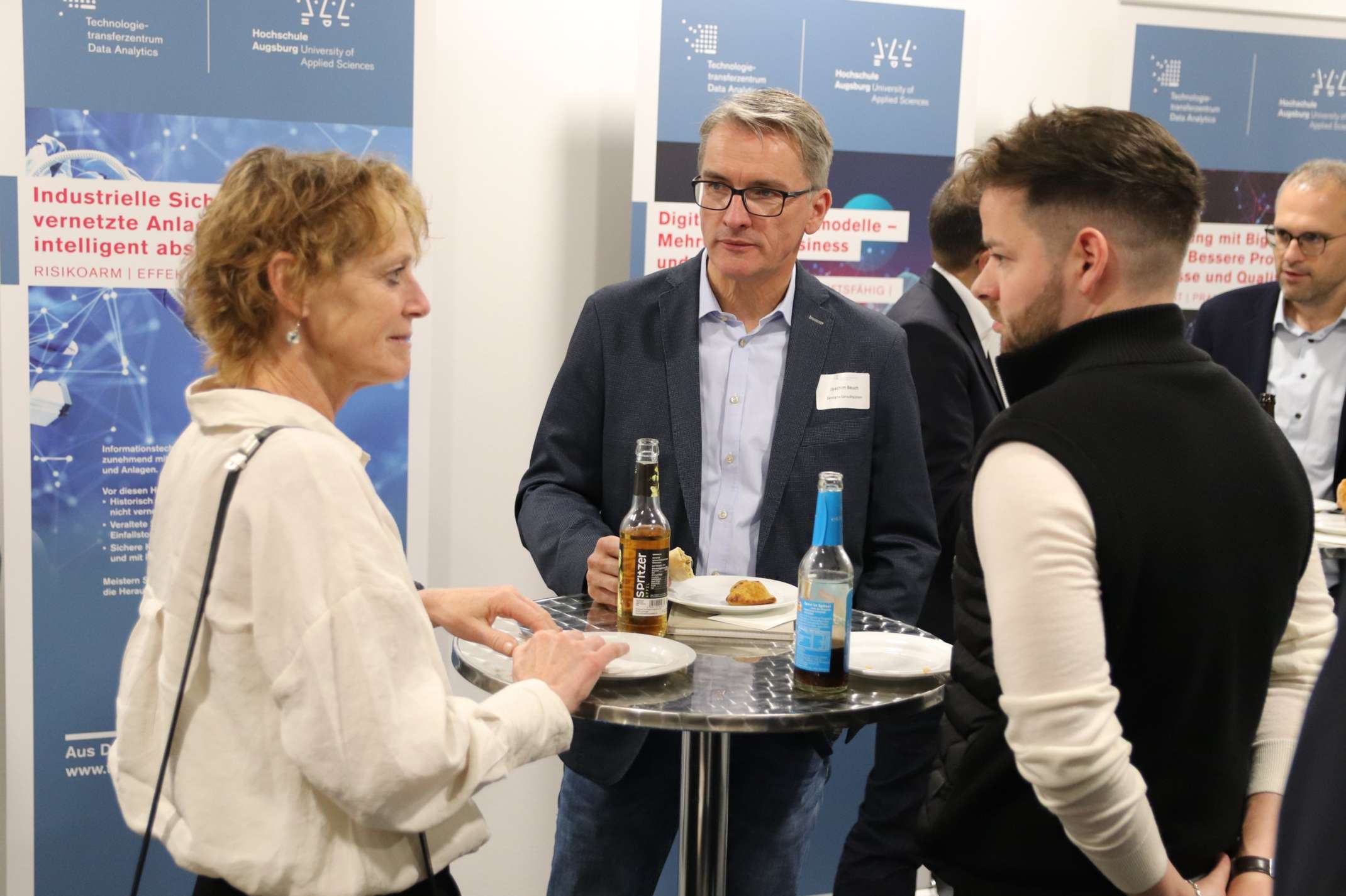 Teilnehmende im Gespräch vor Roll-Ups