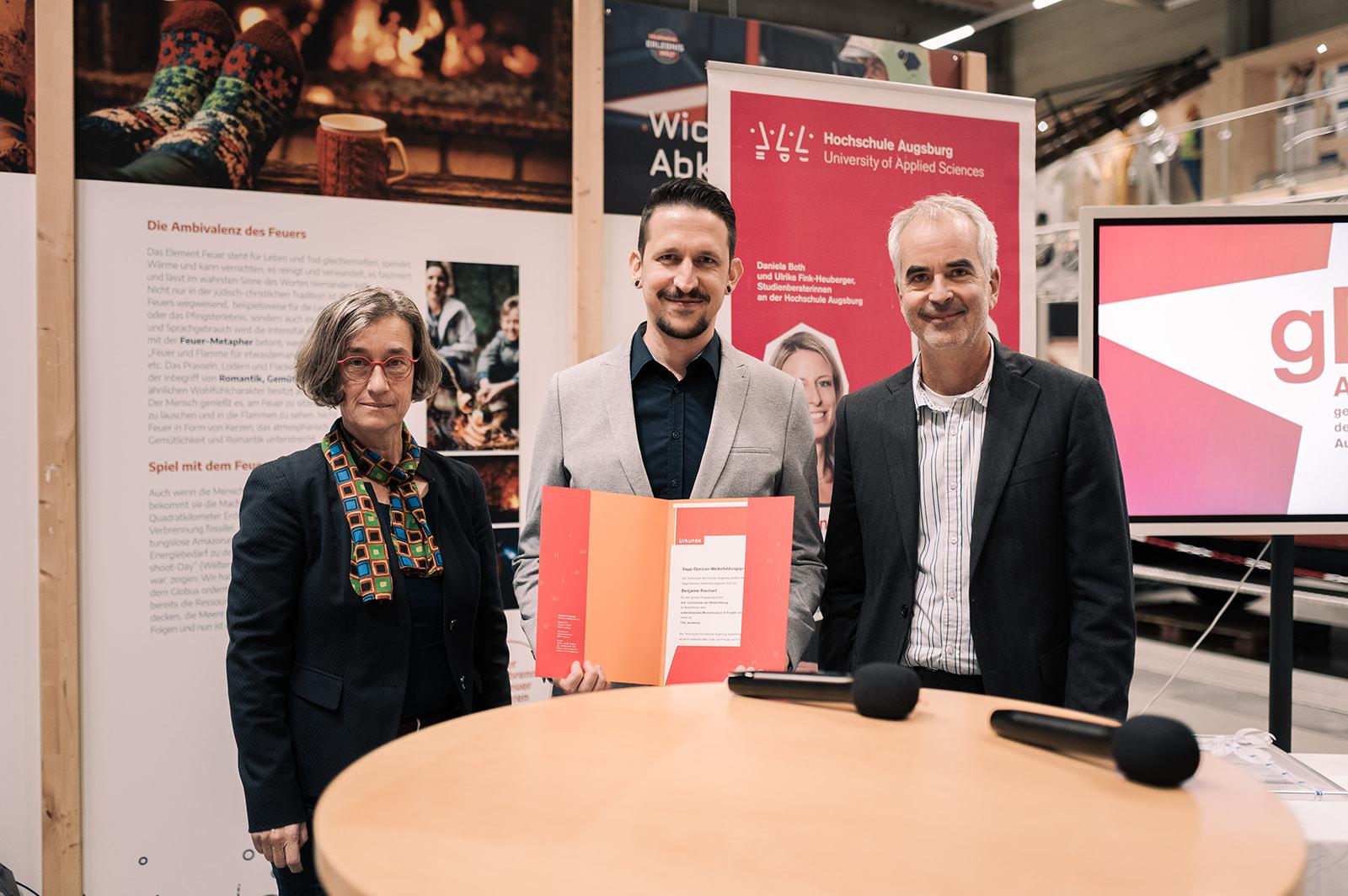Benjamin Reichart erhielt aus den Händen von Professorin Elisabeth Krön und Professor Clemens Espe den Sepp-Starzner-Weiterbildungspreis 2023. 