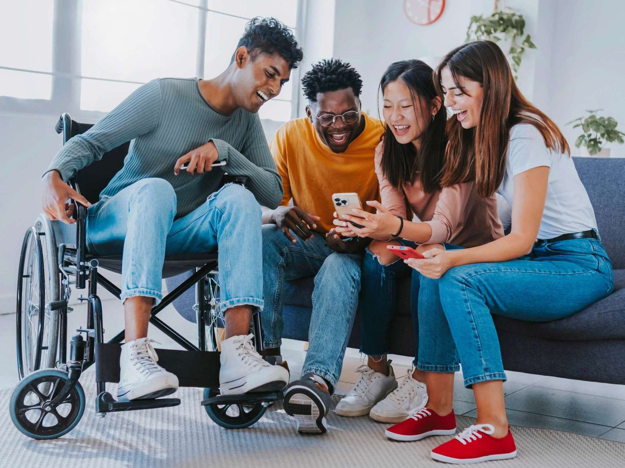 Studenten auf Couch und in Rollstuhl mit Handy