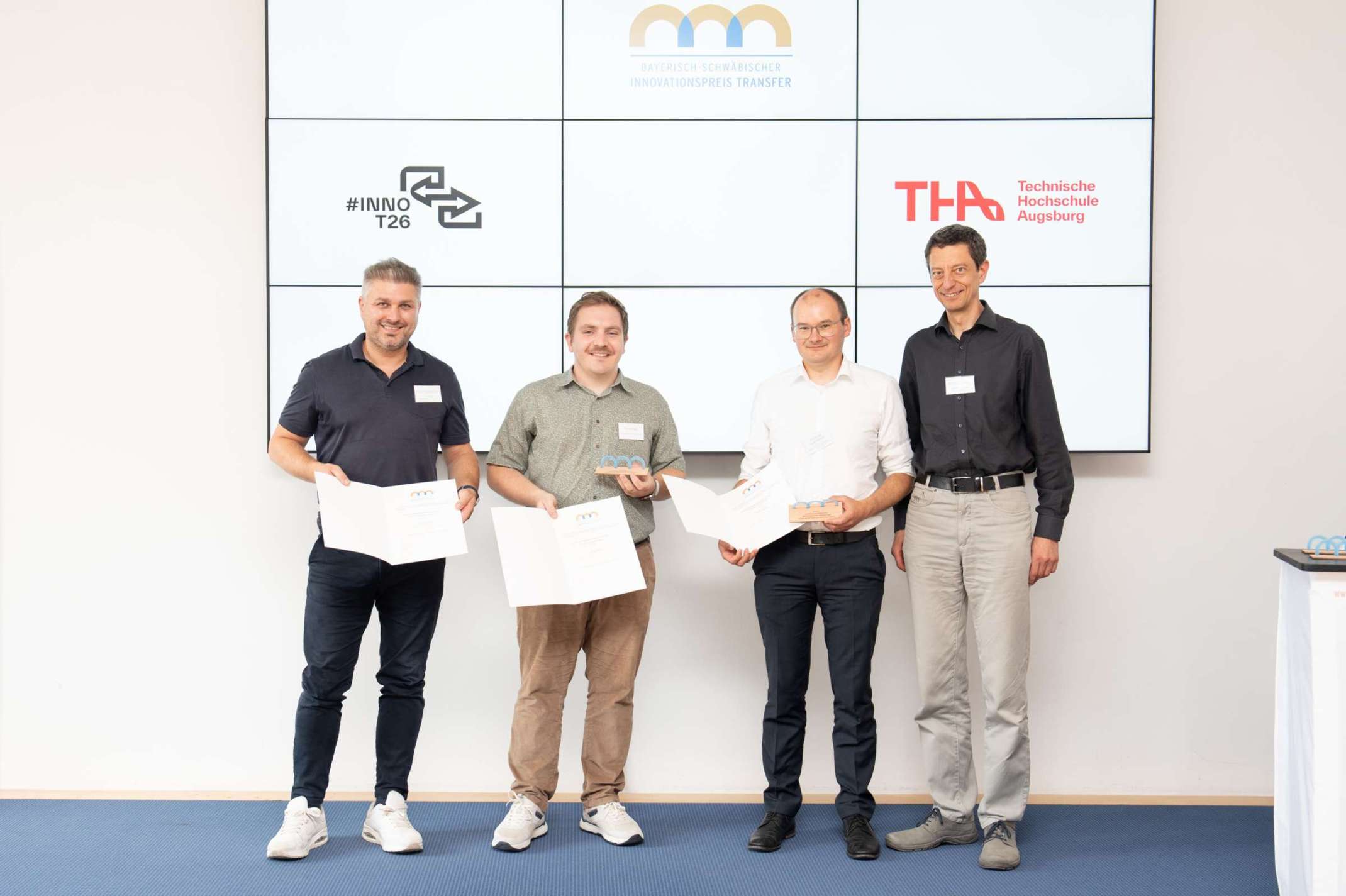 #InnoT26: Das Siegerteam des Transferprojekts GiFaTex der Technischen Hochschule Augsburg (v.l.n.r.): Prof. Dr.-Ing. Mesut Cetin, Professor für Maschinen und Verfahren der Kreislaufwirtschaft faserbasierter Produkte an der Fakultät für Maschinenbau und Verfahrenstechnik der THA / Geschäftsführung des ITA Augsburg – Institut für Textiltechnik Augsburg GmbH, Vincent Mack, M.Eng., Promovend am TTZ Aichach, Prof. Dr.-Ing. Sergej Rempel, THA / wissenschaftlicher Leiter im Forschungsfeld Massivbau am TTZ Aichach, Prof. Dr. phil. habil. László Kovács, Vizepräsident für Studium und Lehre der THA. © Julia Liebhardt