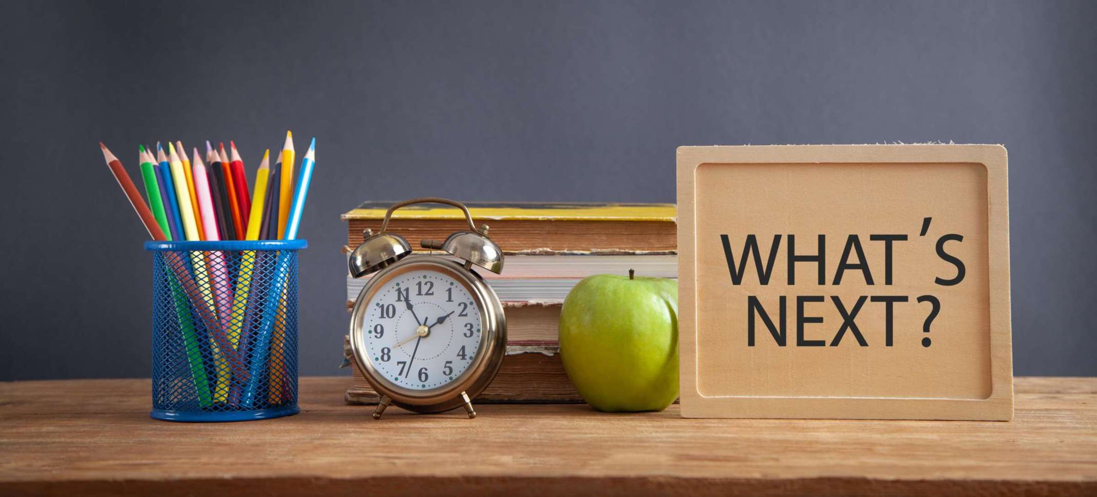 Tisch mit verschiedenen Schulutensilien darauf und der Frage "What's Next?" Tisch mit verschiedenen Schulutensilien darauf und der Frage "What's Next?"