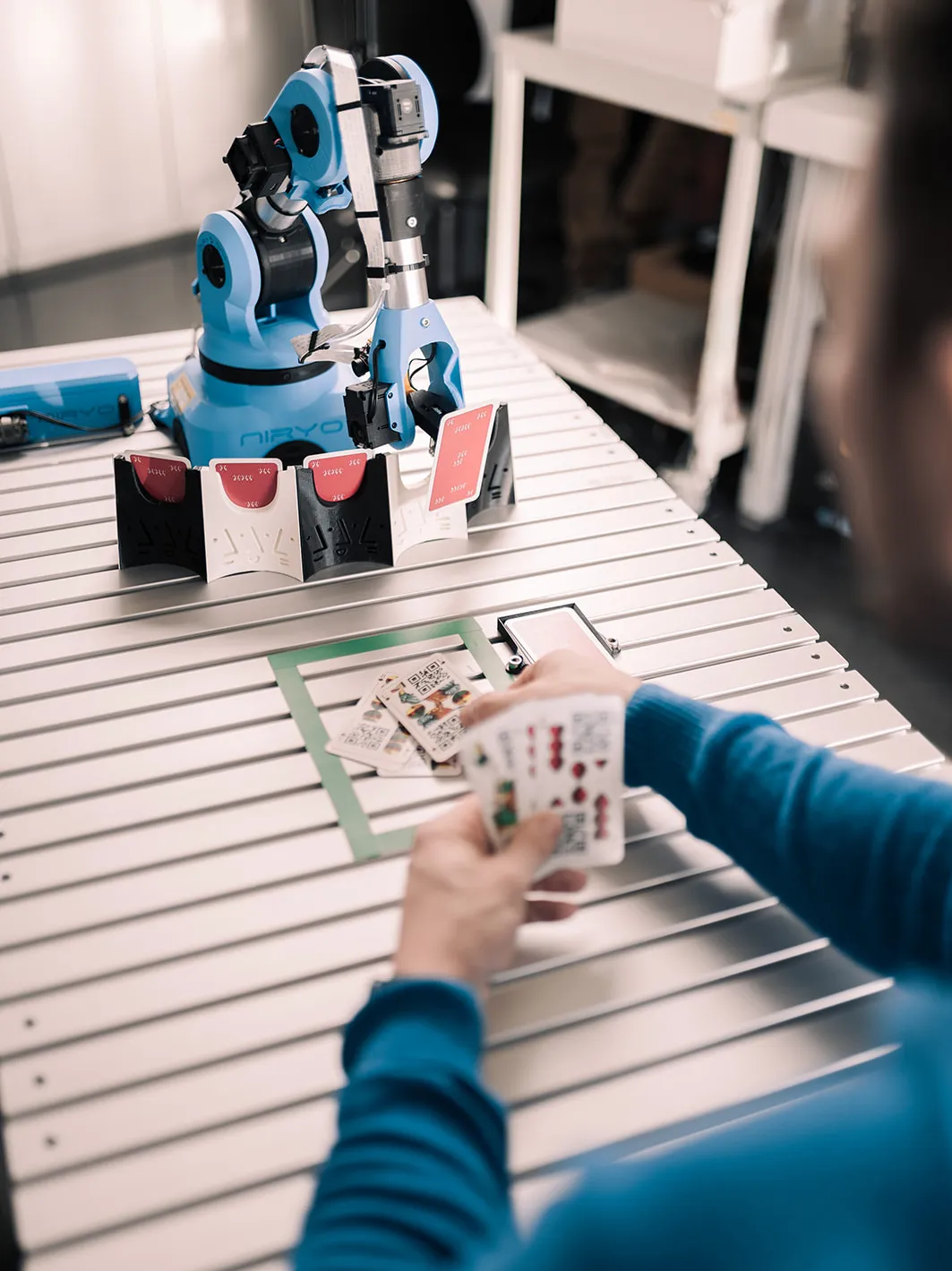 Studierender spielt Kartenspiel gegen einen Roboter.
