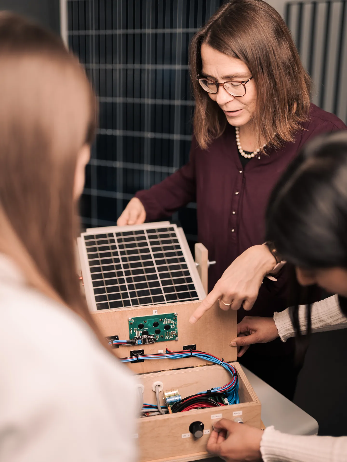Professorin und Studierende an Versuchsaufbau zur Photovoltaik