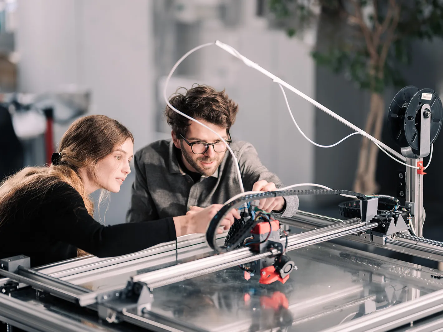 Two researchers are working together to develop and test a 3D printer in a state-of-the-art research laboratory at the Technical University of Applied Sciences Augsburg.