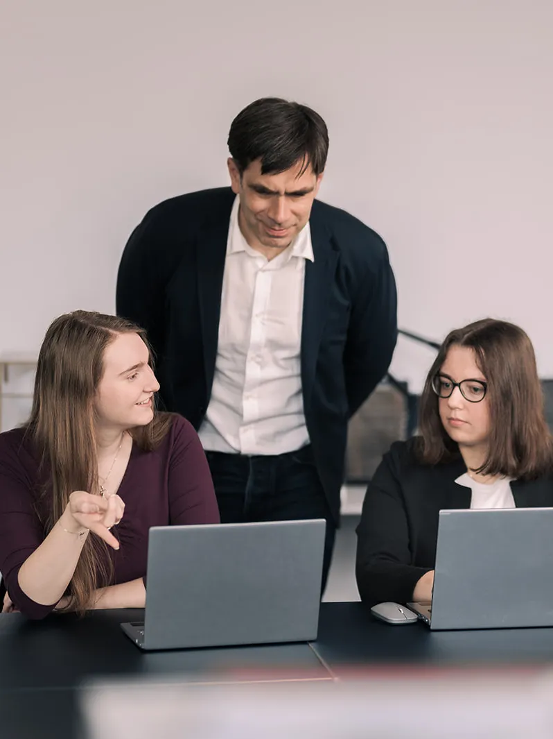 Studierende besprechen sich mit Professor am Laptop