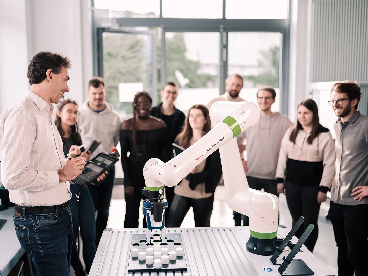 daniel-fuerst-hoch3media-robotik Studierendengruppe mit dem Professor bei einem Versuch mit dem Roboter.