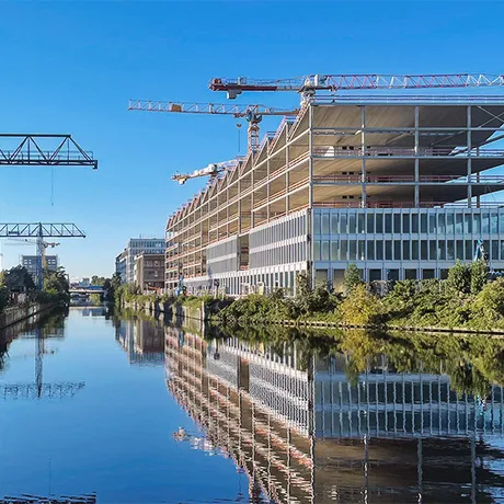 Baustelle am Wasser mit Baugerüst und Baukränen.