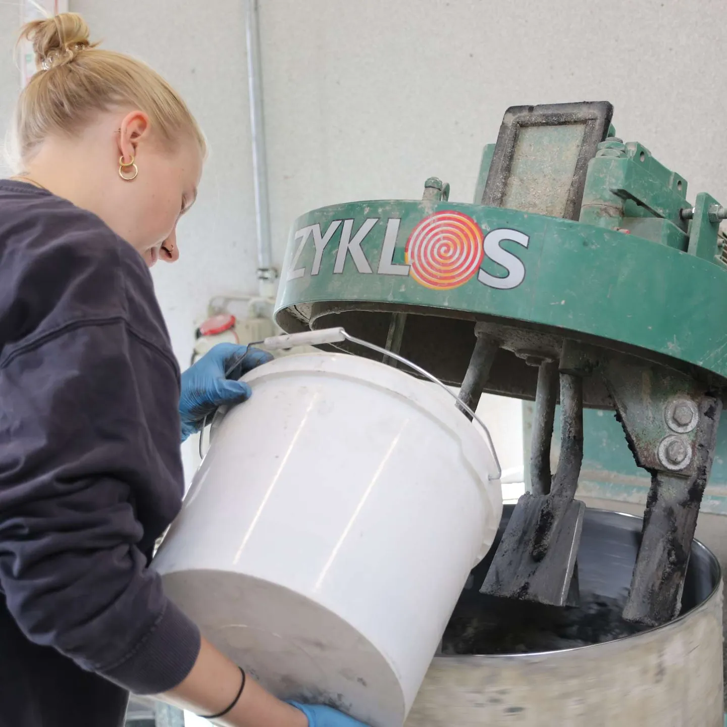 Studentin schüttet Material in Betonmischer