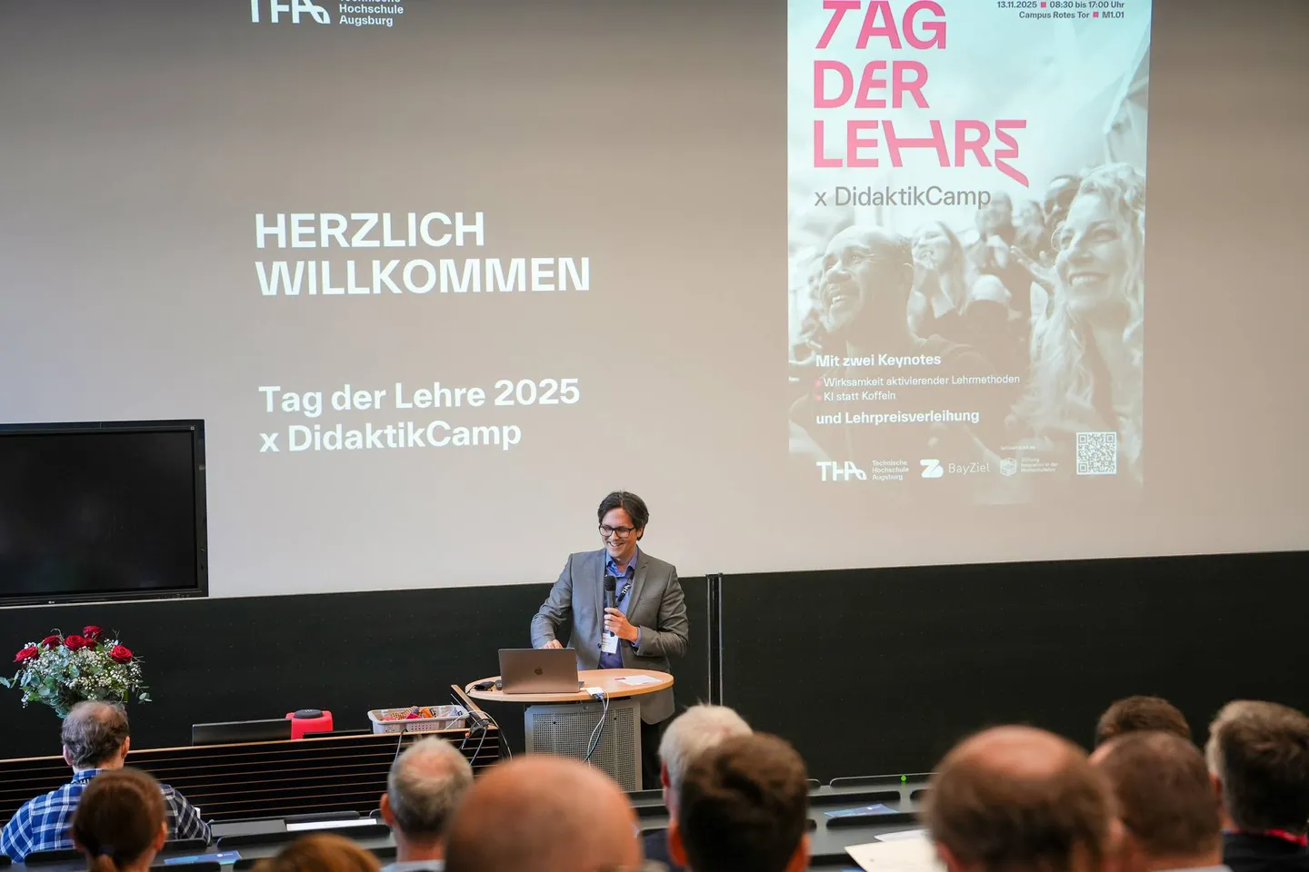 Blick über die Publikumsreihen auf die Bühne mit der Begrüßungsfolie des Tags der Lehre