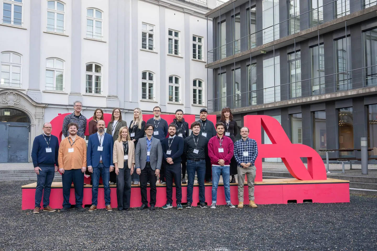 Gruppenfoto des DMZ-Teams im Innenhof vor dem pinken THA-Schriftzug