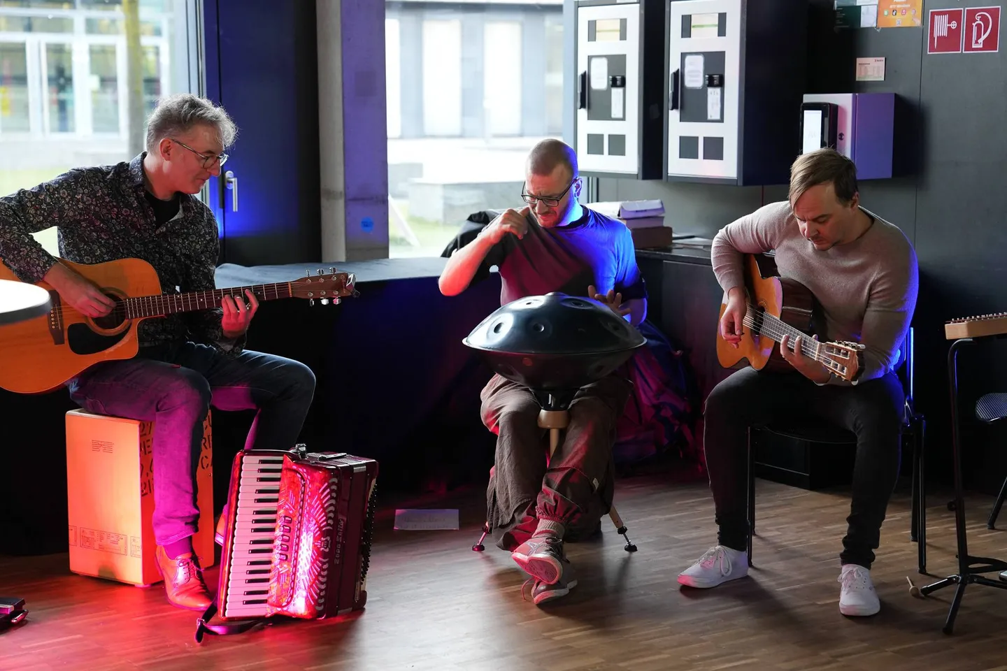 Drei Musiker des Ensembles Sphärenschmiede spielen Gitarre, Akkordeon und Handpan