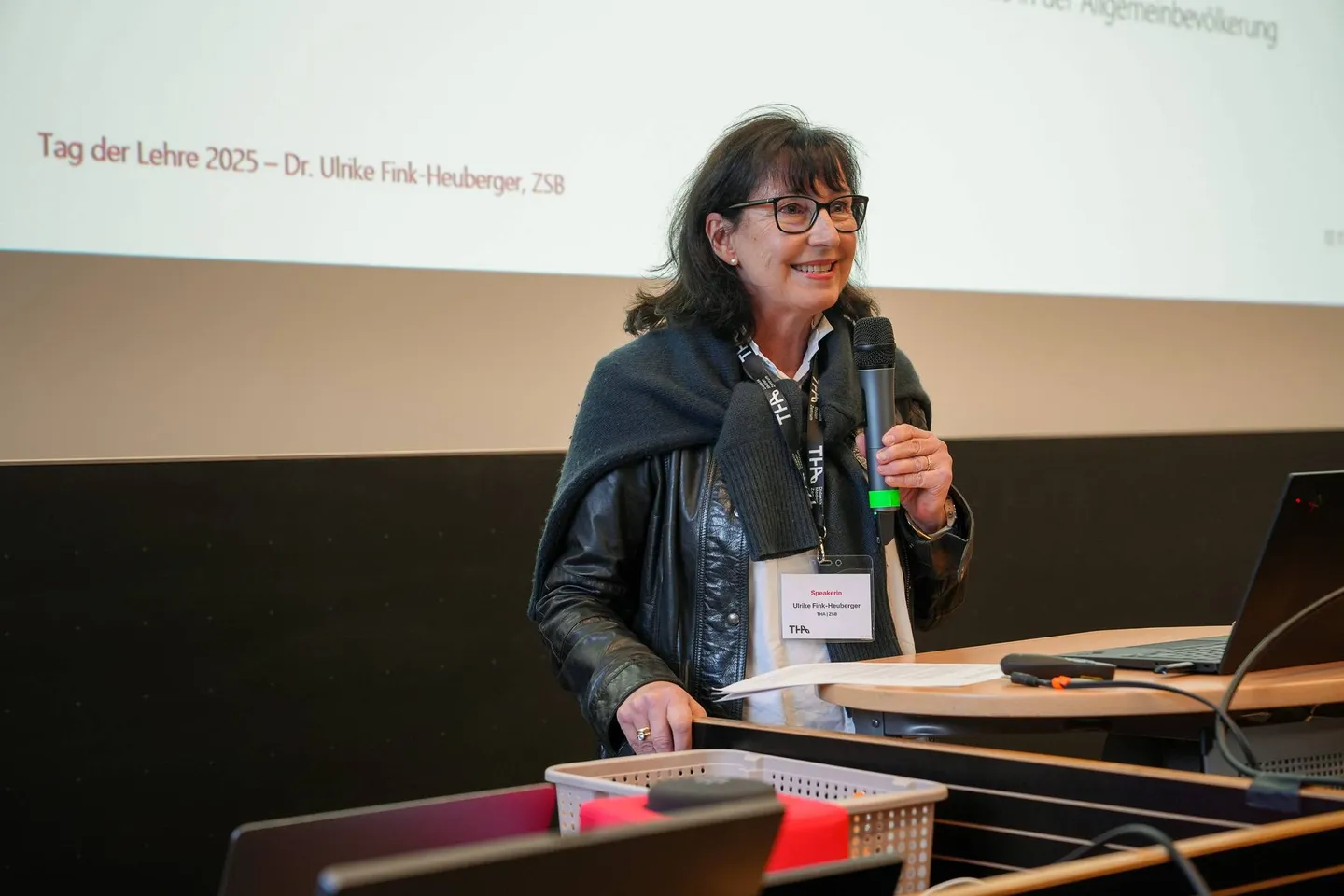 Dr. Ulrike Fink-Heuberger spricht mit Mikrofon vor ihrer Titelfolie