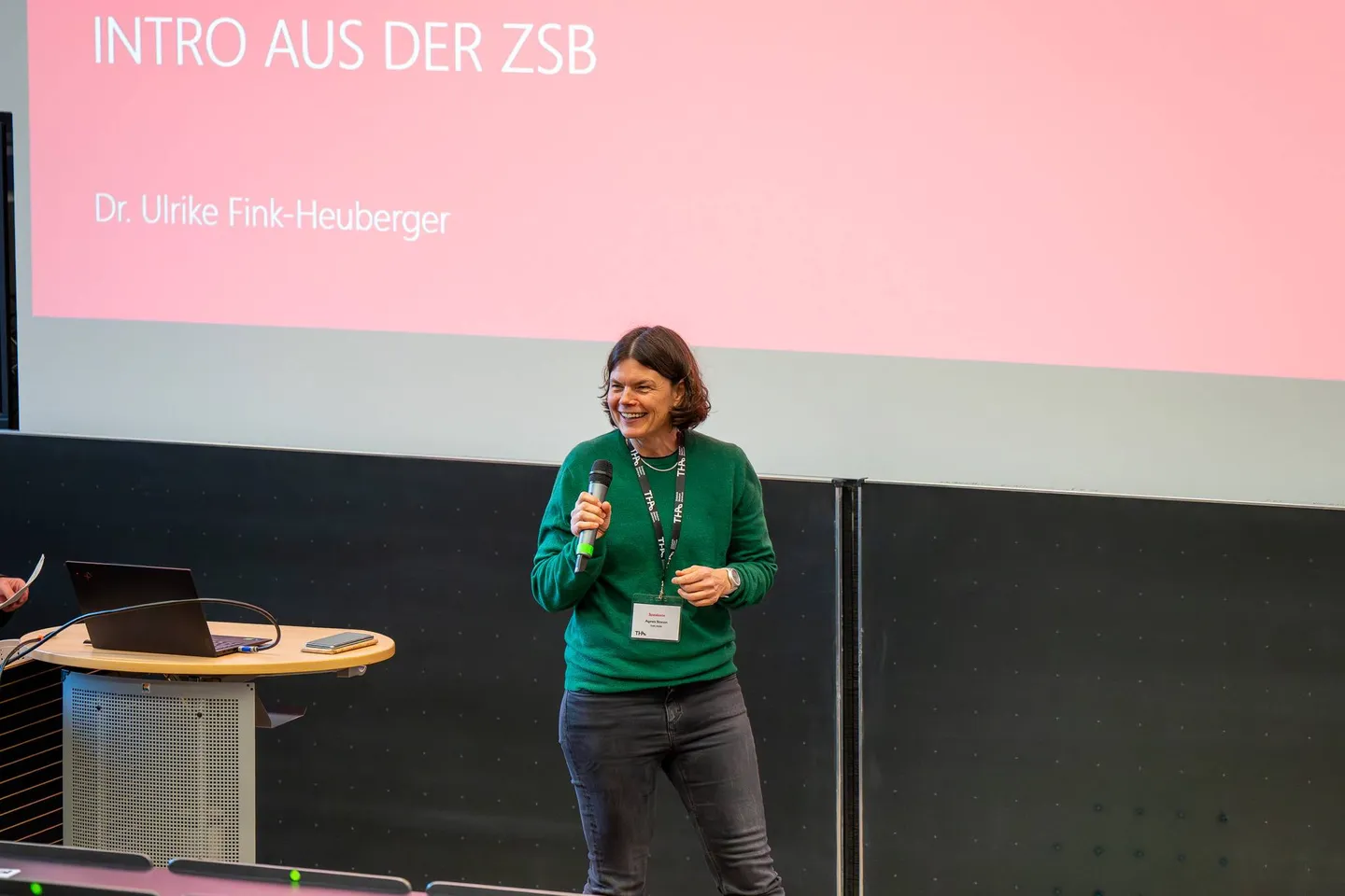 Vortragende spricht im Hörsaal, im Hintergrund die Folie „Intro aus der ZSB“