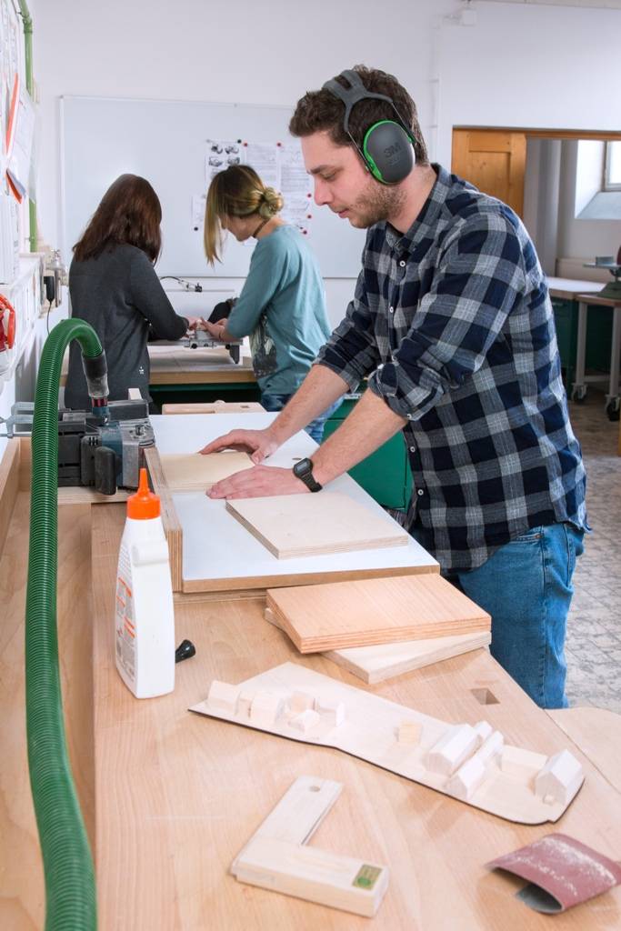 Studierender arbeitet an Holzplatte