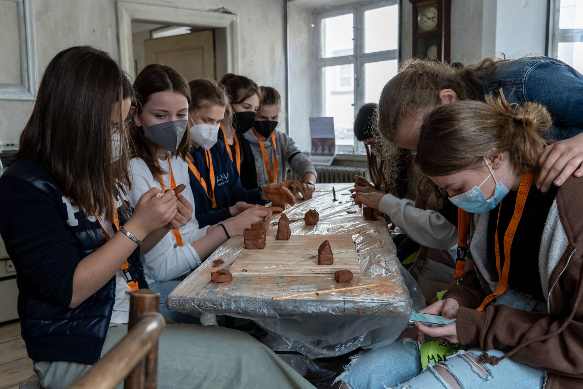 Schülerinnen arbeiten an ihren Lehmhäusern