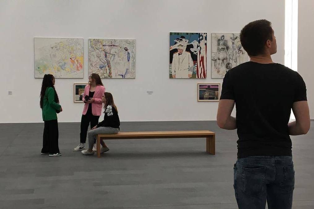 Personen in einer Ausstellungshalle mit Gemälden