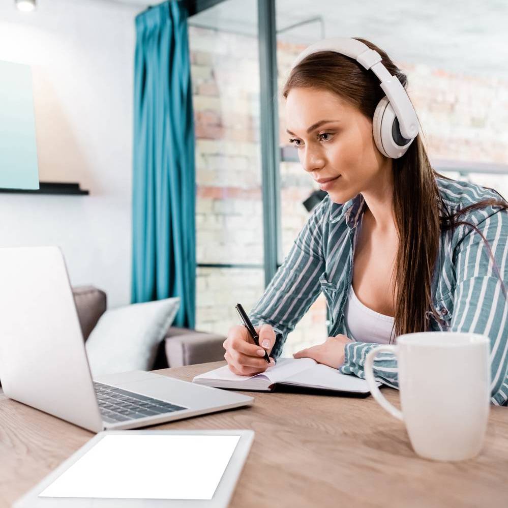 Junge Frau mit Kopfhörern vor einem Laptop. Foto: Colourbox