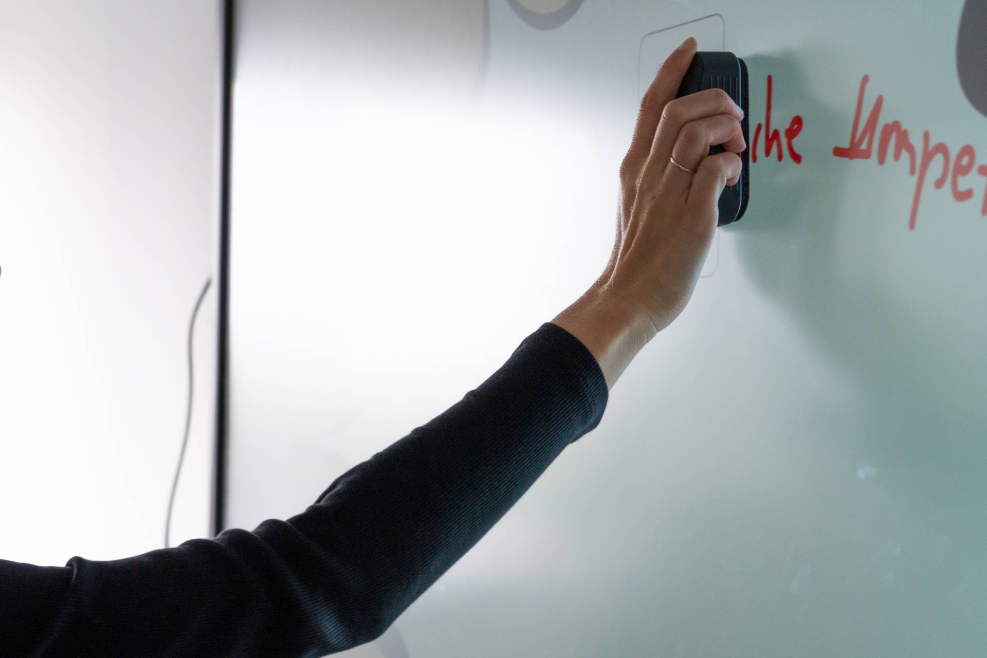 Hand wischt mit dem Schwamm auf dem ViewBoard