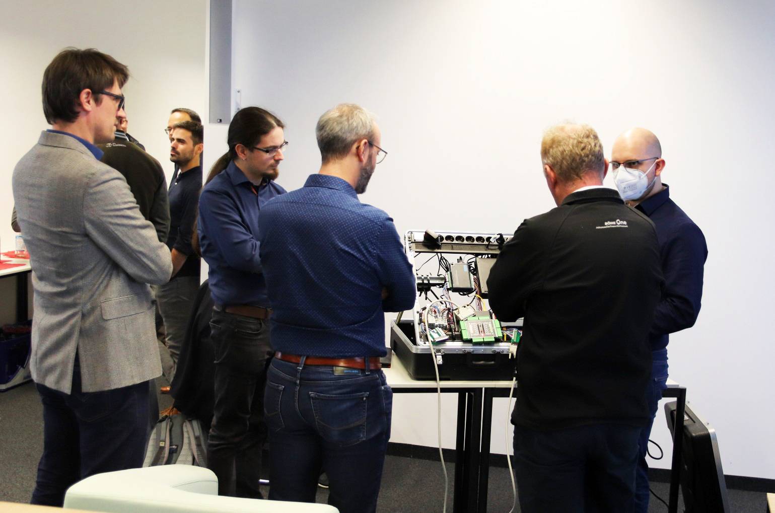 Teilnehmende aus der Industrie und Forschende der Hochschule Augsburg im Gespräch zu einem Demonstratoraufbau