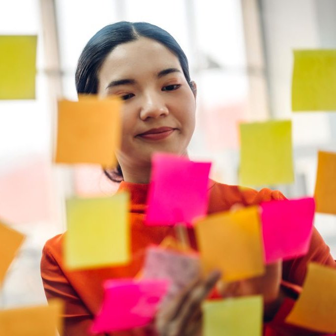 Asiatische Studentin sortiert verschiedenfarbige Postits