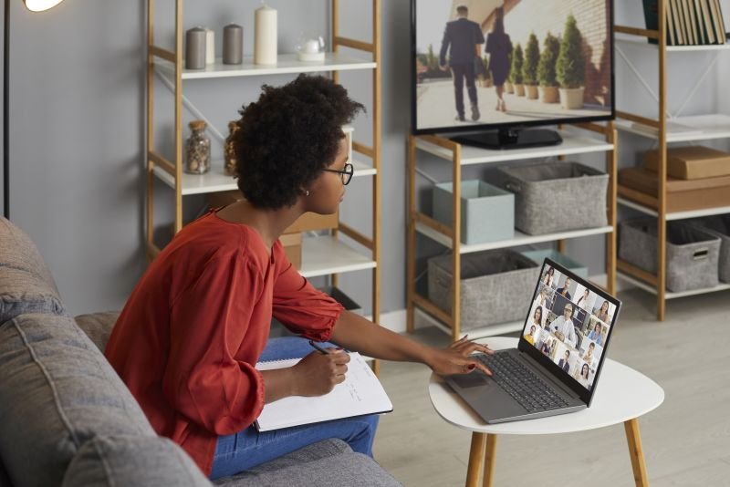 Studentin sitzt auf der Couch und schaut sich ein Webinar am Laptop an