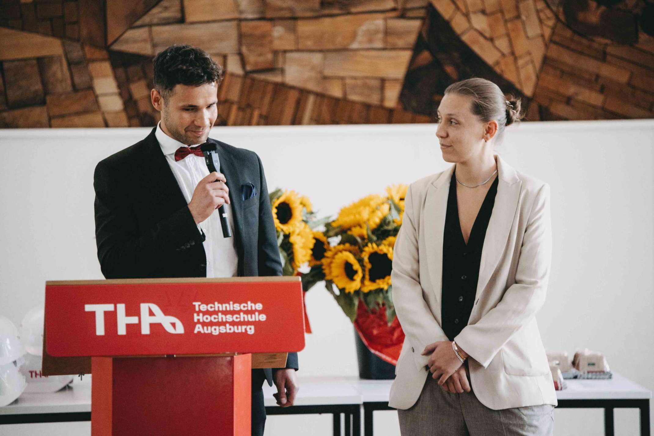 2_Semestersprecherin und Semstersprecher des Masterstudiengangs Projektmanagement Bau sprechen ein Grußwort. Foto: Matthias Leo