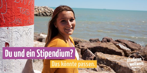 Studentin steht an einer felsigen der Küste und lächelt in die Kamera