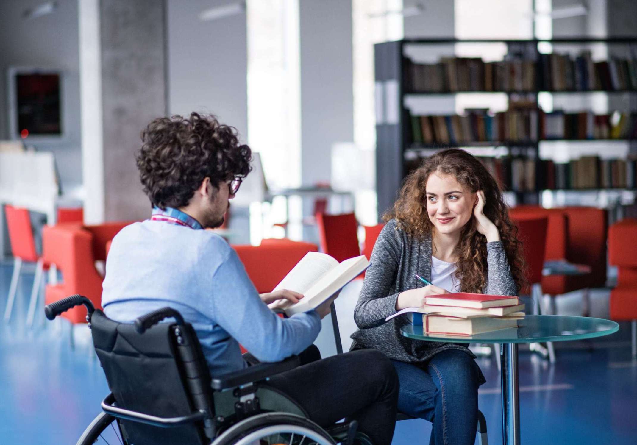 Studierende mit sichtbarer und unsichtbarer Behinderung am Campus mit Büchern auf dem Tisch