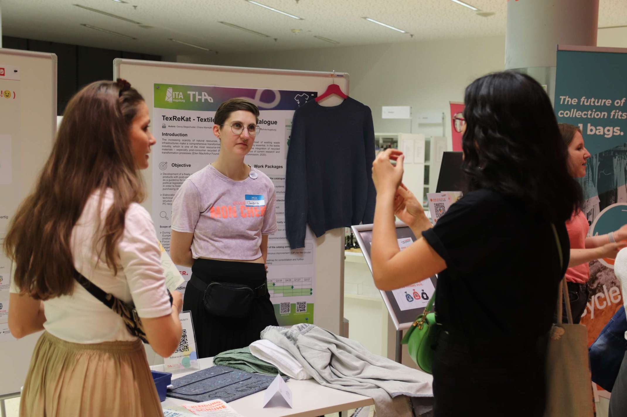 Eine Besucherin mit TexReKat-Vertreterin Chiara Warmuth (ITA Augsburg) im Gespräch über Recyclingmaterialien. Eine Besucherin mit TexReKat-Vertreterin Chiara Warmuth (ITA Augsburg) im Gespräch über Recyclingmaterialien.